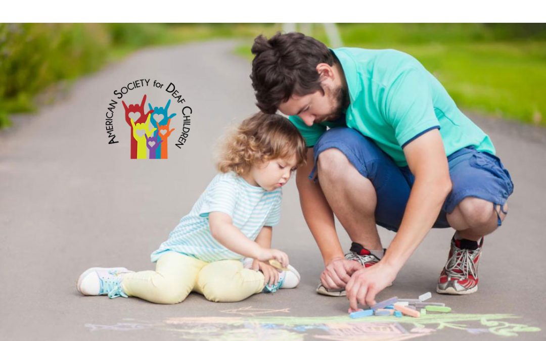father with his young daughter outside drawing with chalk on a sidewalk