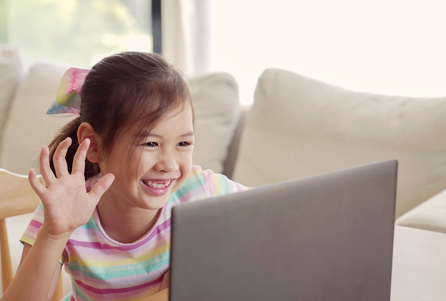 young girl looking at computer with her hand up