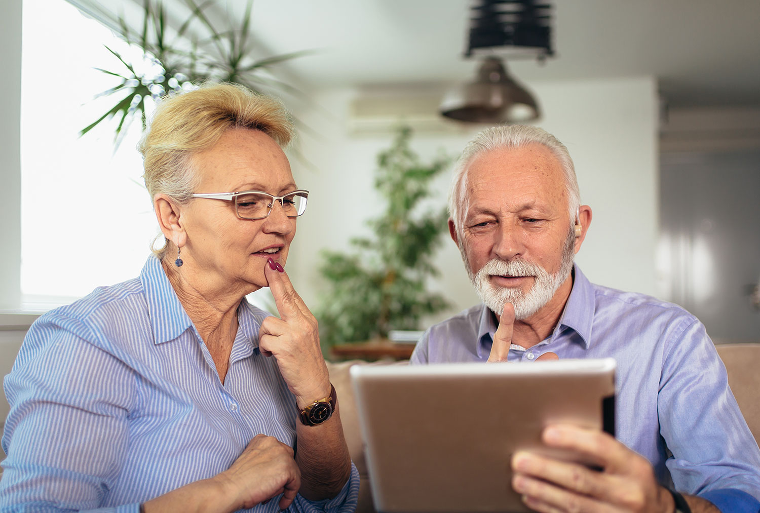 older couple holding a tablet and signing to someone on the screen