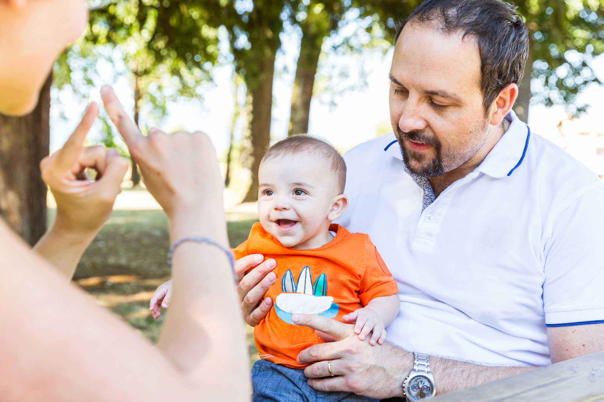 La imagen muestra a los padres usando el lenguaje de señas para comunicarse con su bebé feliz.