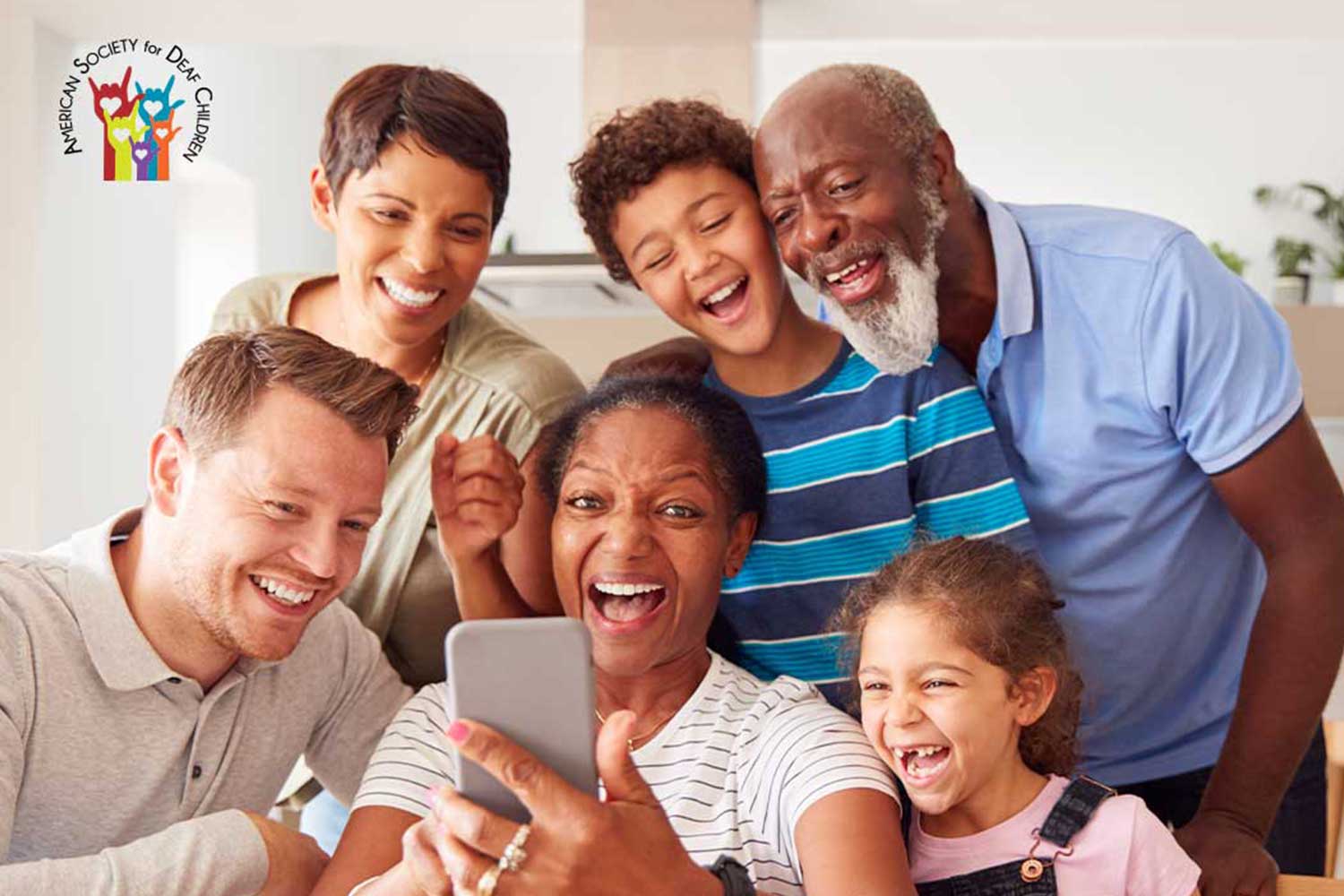 image shows a happy, multigenerational family taking a selfie or talking to someone through video chat