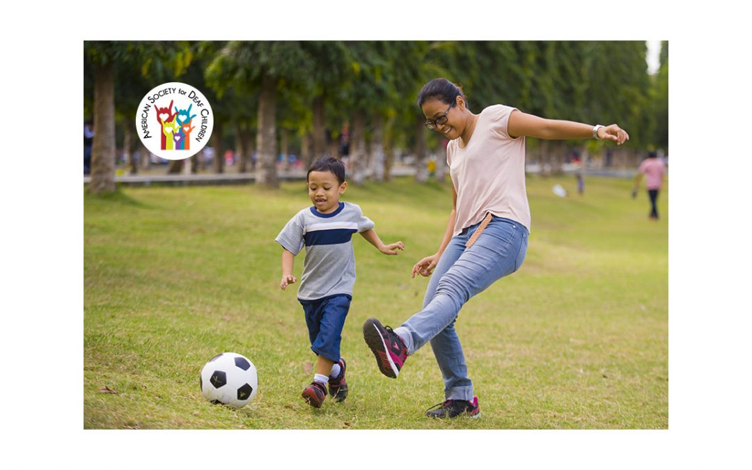 image shows a mother and son playing soccer in a park