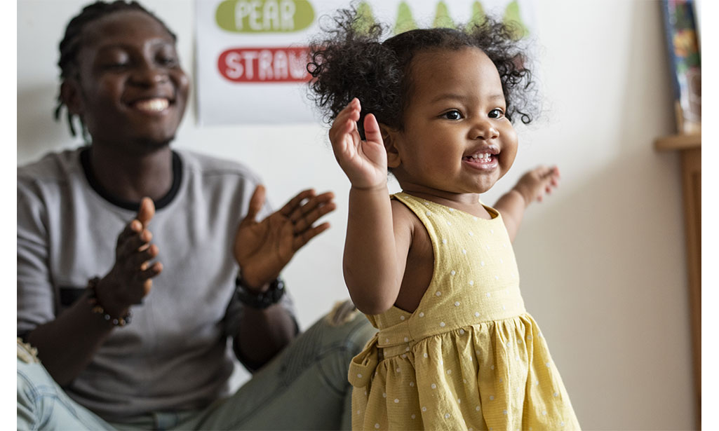 A father is clapping for his infant daughter